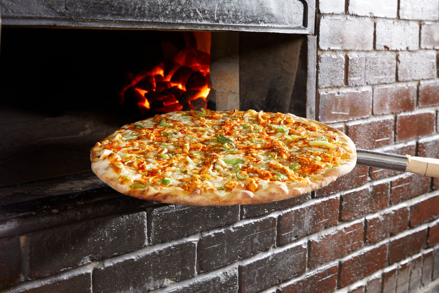 Buffalo Chicken Pizza coming out of a brick oven